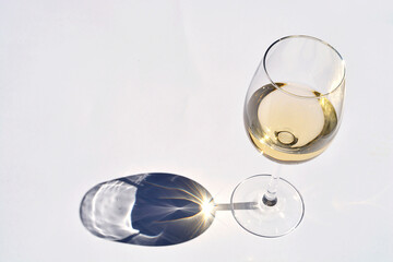 A high angle view of  a glass of white on the table under the sun lights  with abstract shadow effect and reflection