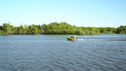 A motor boat floats on a blue river. Water transport moves quickly.
