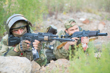 Fototapeta premium Two teammates of the airsoft player aim towards the enemy