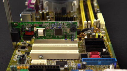 Obraz premium Installing a network card on the motherboard. Network data transmission system via wire. Many different chips. View of the computer parsed