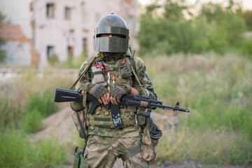 Fototapeta premium Professional airsoft player stands in a big helmet and a machine gun