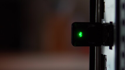 Usb modem wifi inserted into the computer close-up. The modem flashes a green light. Computer view from the back.