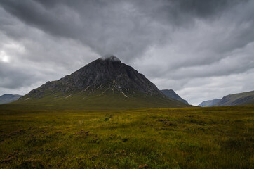Mountain landscape in the Glen Coe with dark clouds hanging over the peaks, Highland, Scotland