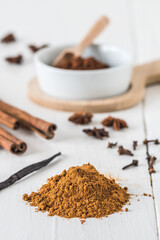 Baking spices like cinnamon, star anise, cocoa and vanilla bean on white wooden table. Vertical stock photo.