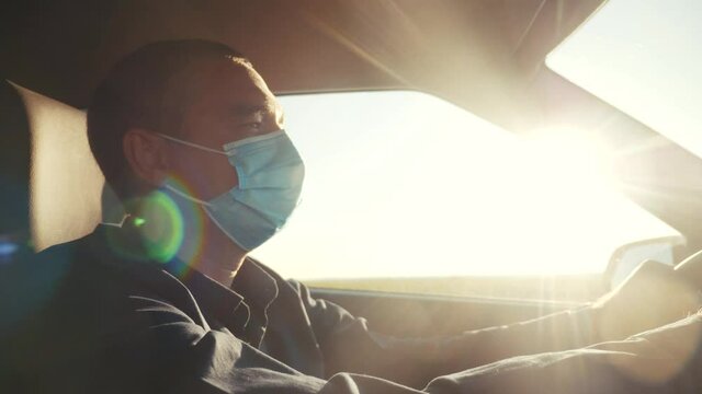 worker driver wearing medical mask taxi drives a car during the coronavirus period. delivery during the pandemic parcel concept. man wearing a mask driver protection against coronavirus