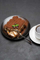 portion of Classic tiramisu dessert and cup of fresh espresso coffee on concrete background