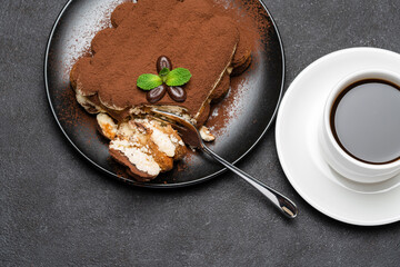 portion of Classic tiramisu dessert and cup of fresh espresso coffee on concrete background
