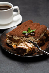 portion of Classic tiramisu dessert and cup of fresh espresso coffee on concrete background