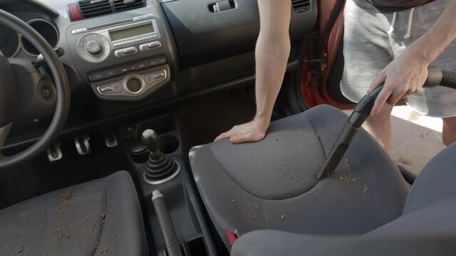 Man cleaning dirty car interior with vacuum cleaner