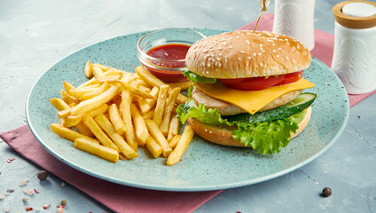 Juicy buregr with cheese and chicken on a plate with fries and sauce