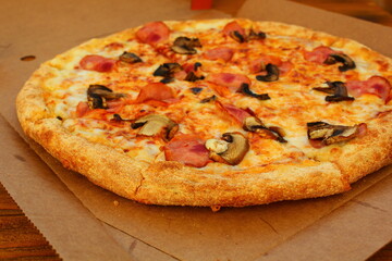 fresh pizza with mushrooms and sausage in a box on the table