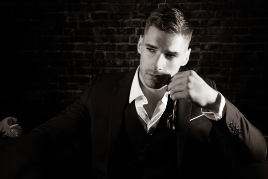 Portrait of handsome man wearing tuxedo with open shirt looking away from camera