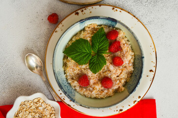 Delicious oatmeal porridge with ripe raspberries. Healthy and hearty Breakfast. The concept of diet and vegetarian food for a slim figure lifestyle