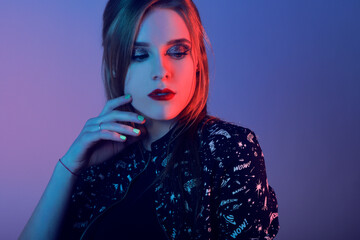 Model with air style. Woman in colorful bright lights posing in studio, portrait of beautiful girl with trendy make-up and manicure. Art design, colorful make up. Over colourful blue background.