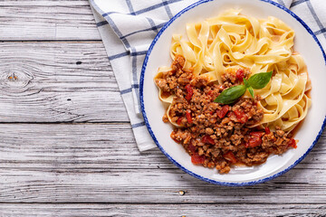 Traditional italian pasta bolognese on a white plate on a wooden background