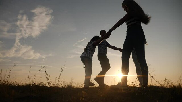 happy family mom dad and daughter play round dance silhouette at sunset. people in park kid dream concept. happy family parents with little kid child daughter play in park on grass holding hands fun