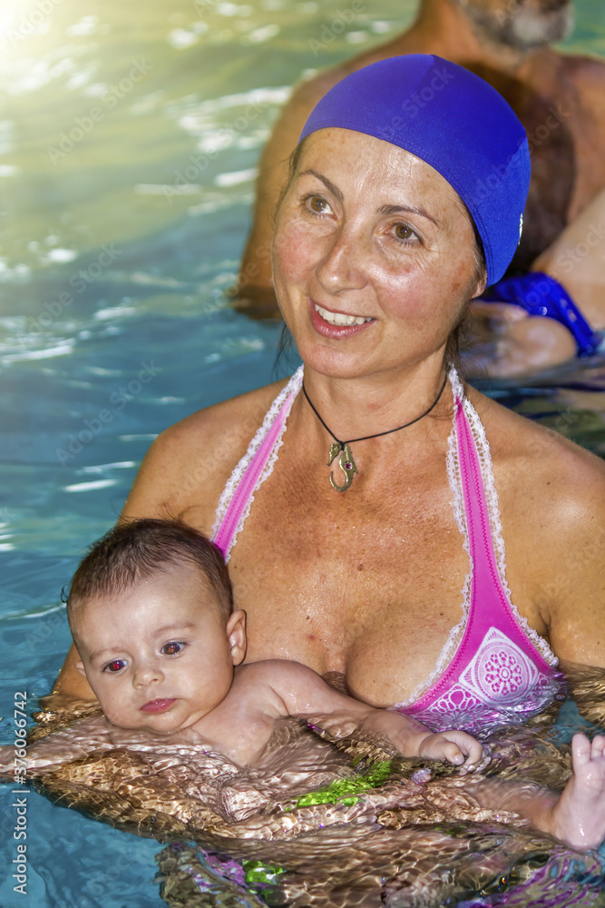 Poster Happy woman in the children pool holding her little daughter