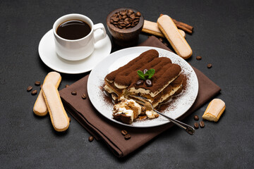 portion of Classic tiramisu dessert and cup of fresh espresso coffee on concrete background