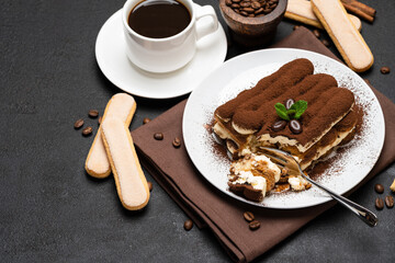 portion of Classic tiramisu dessert and cup of fresh espresso coffee on concrete background