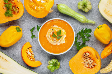Pumpkin soup and various vegetables on a dark background. Top view.