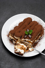 portion of Classic tiramisu dessert on ceramic plate on concrete background