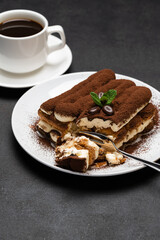portion of Classic tiramisu dessert and cup of fresh espresso coffee on concrete background