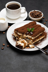 portion of Classic tiramisu dessert and cup of fresh espresso coffee on concrete background