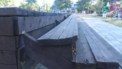empty wooden texture bench fading into the distance in perspective view to blurred background of playground with unrecognizable figures of children playing