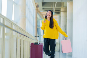 Happy asian woman holding shopping bags and smiling at airport.