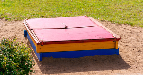 children closed sandbox on yellow sand in playschool overhead view