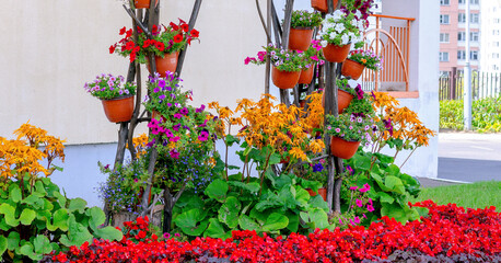 Fototapeta na wymiar decorative colored multilevel flowerbed with vases with bright flowers at city street
