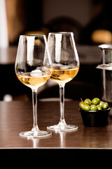 glasses with wine and olives, on the wooden table, inside the restaurant and free space for decoration.