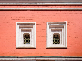 An old red brick wall with two Windows.