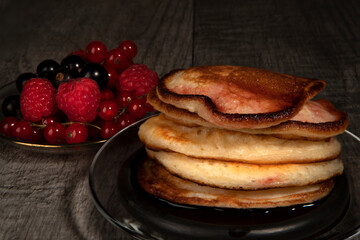Several pancakes with different berries on wood background