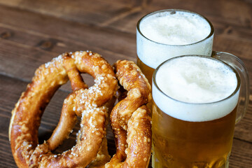 Cup of mugs of light beer, pretzels on the wooden background. Beer and pretzels as symbol of October fest.