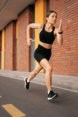 Young woman sprinting in the morning outdoors. Top view of female runner working out in the city.