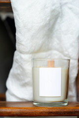 Elegant home decoration with wooden wick burning candle from soy wax. High quality photo. on a background of white linen fabric