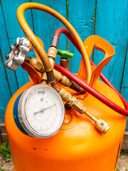 Refrigerant cylinder and hoses with pressure gauge. Orange bottle with freon. Pressure gauge for...