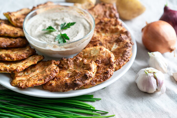 .Potato pancakes, golden, on a white plate. Garlic sauce, fresh herbs, with ingredients.