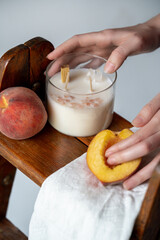The candle is handmade from soy wax with the scent of peaches on a wooden stand. High quality photo
