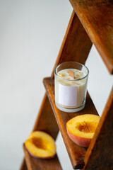 The candle is handmade from soy wax with the scent of peaches on a wooden stand. High quality photo