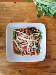 View from the top of Papaya Salad with crab and fermented fish served with vegetables on a wooden table. Spicy Thai food that contains Small chopped bitter gourd, tomato, fresh chili and spicy sauce

