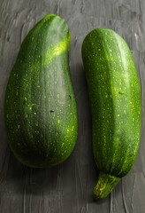 On a black background lie two courgettes of green and different widths