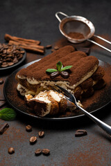 portion of Classic tiramisu dessert on ceramic plate on concrete background
