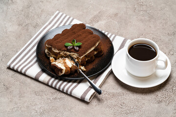 portion of Classic tiramisu dessert and cup of fresh espresso coffee on concrete background