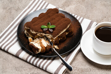portion of Classic tiramisu dessert and cup of fresh espresso coffee on concrete background