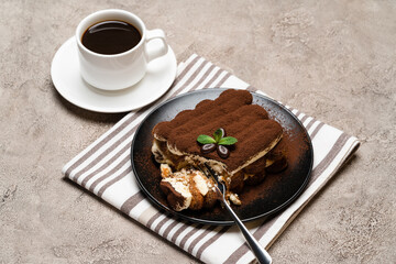 portion of Classic tiramisu dessert and cup of fresh espresso coffee on concrete background