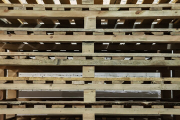 Stacked used wooden pallets in warehouse. Stacks of Euro-type cargo pallets. Background of wooden pallets. Concept of warehousing and storage of goods