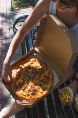 Beautiful, young woman eating pizza in the street. The concept of fast food, food delivery and lunch in nature