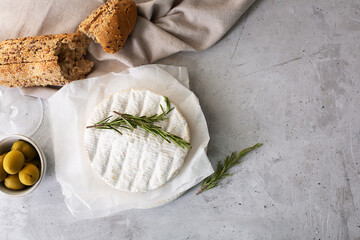 Camembert cheese with fruits, nuts and berries on a gray background